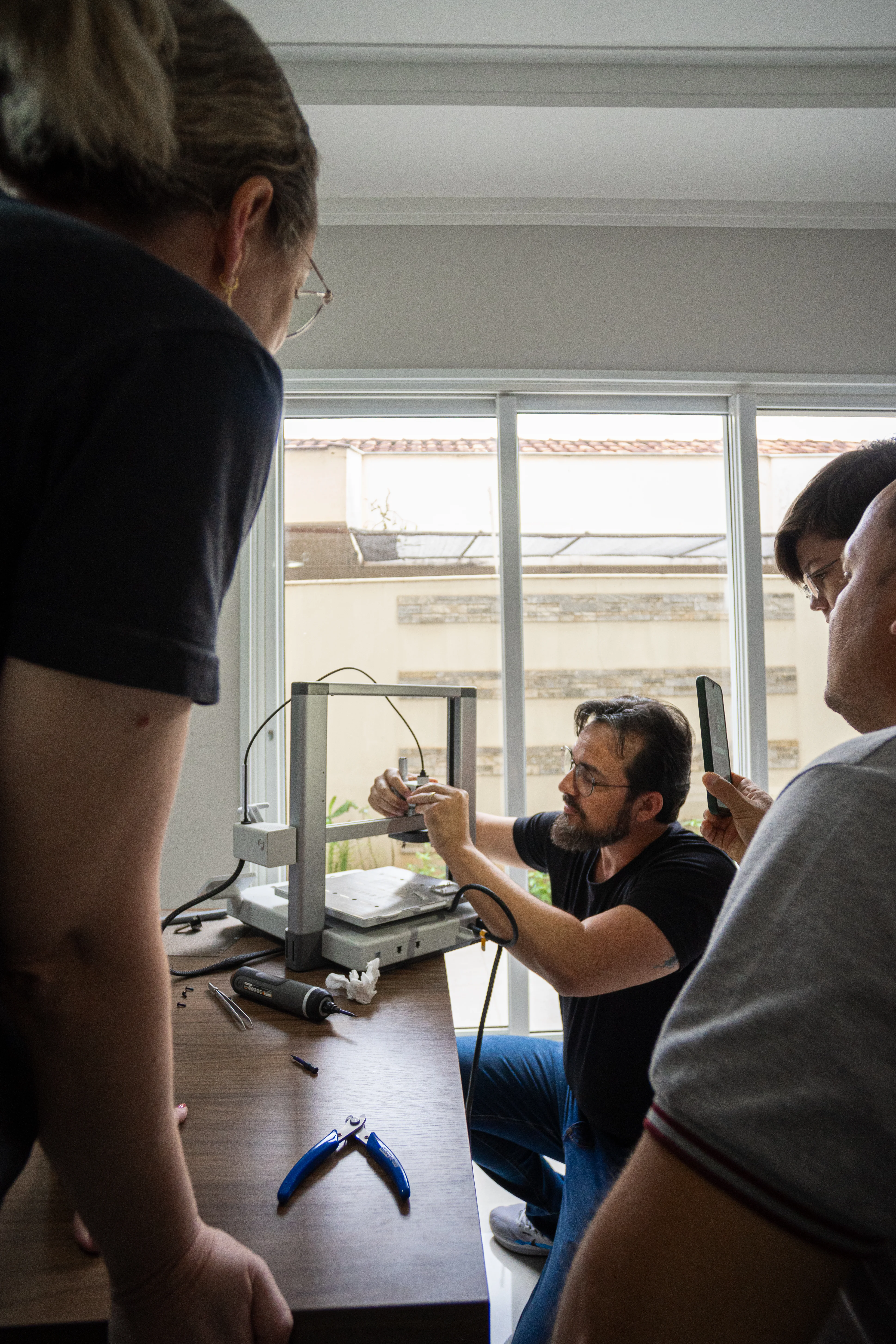 Everton ajusta uma impressora 3D diante dos participantes em uma experiência presencial da Vieco